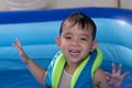 Happy Funny Baby Boy Kid Toddler wearing life jacket playing water in the pool Royalty Free Stock Photo