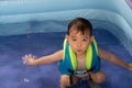 Happy Funny Baby Boy Kid Toddler wearing life jacket playing water in the pool Royalty Free Stock Photo