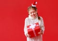Happy funny child girl    with Christmas gift on red   background Royalty Free Stock Photo