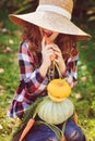 Happy funny child girl in farmer hat and shirt playing and picking autumn vegetable harvest in sunny garden