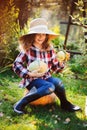 Happy funny child girl in farmer hat and shirt playing and picking autumn vegetable harvest Royalty Free Stock Photo