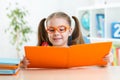 Happy funny child girl in glasses reading a book Royalty Free Stock Photo