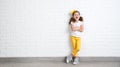 Happy funny child girl near an empty brick wall