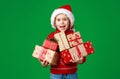 Happy funny child girl in red Christmas hat   with gift on green   background Royalty Free Stock Photo