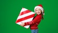 Happy funny child girl in red Christmas hat   with gift on green   background Royalty Free Stock Photo