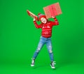Happy funny child girl in red Christmas hat   with gift jumping on green   background Royalty Free Stock Photo