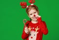 Happy funny child girl in red Christmas reindeer costume with gift on green   background Royalty Free Stock Photo