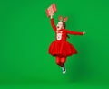 Happy funny child girl in red Christmas reindeer costume jumping  with gift on greeen   background Royalty Free Stock Photo