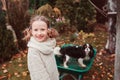 Happy funny child girl riding her dog in wheelbarrow in autumn garden, candid outdoor capture Royalty Free Stock Photo