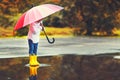 Happy funny child girl with umbrella jumping on puddles in rubb Royalty Free Stock Photo