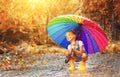 Happy funny child girl with umbrella jumping on puddles in rubb Royalty Free Stock Photo