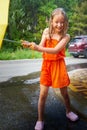 Happy funny child with yellow umbrella under the summer rain. Girl enjoying rainfall. Kid playing on the nature outdoors Royalty Free Stock Photo