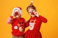 Happy funny emotional children boy and girl in red Christmas reindeer costume on yellow background