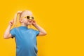 Happy funny fair-haired cheerful little girl wear sunglasses and blue t-shirt on yellow background. copy space, mock up