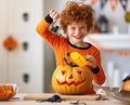 Happy redheaded boy in costume laughs and with spider and pumpkin Jack o lantern during a Halloween celebration