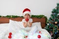 Happy funny girl sitting on the bed on Christmas morning with New Year's decorations Royalty Free Stock Photo