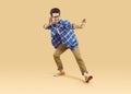 Happy, funny, joyful student in casual clothes and glasses dancing on a beige studio background Royalty Free Stock Photo