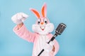 Happy funny kid boy or girl singer or vocalist sings song to retro vintage classic microphone. Easter bunny or rabbit or