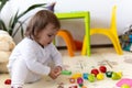 happy funny kid curly baby girl with educational toy blocks flowers. Children play at day care or preschool. Mess in Royalty Free Stock Photo