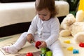 happy funny kid curly baby girl with educational toy blocks flowers. Children play at day care or preschool. Mess in Royalty Free Stock Photo