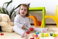 happy funny kid curly baby girl with educational toy blocks flowers. Children play at day care or preschool. Mess in Royalty Free Stock Photo