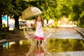 Happy funny kid girl with umbrella jumping on puddles in rubber boots and in polka dot dress Royalty Free Stock Photo