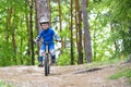 Happy funny little kid boy in colorful raincoat riding his first bike on cold day in forest. Active leisure for children Royalty Free Stock Photo