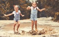 Happy funny sisters twins child by girl jumping on puddles and laughing