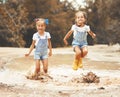 Happy funny sisters twins child girl jumping on puddles in rub Royalty Free Stock Photo