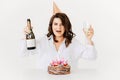 a happy funny woman with champagne and a birthday cake with candles.