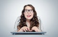 Happy funny young girl programmer in glasses with keyboard in front of computer