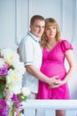 Happy future father with a beautiful cute pregnant woman with flowers. Royalty Free Stock Photo