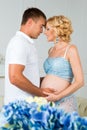 Happy future father with a beautiful cute pregnant woman with flowers. Royalty Free Stock Photo