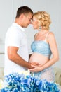 Happy future father with a beautiful cute pregnant woman with flowers. Royalty Free Stock Photo