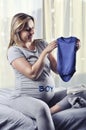 Happy future mommy showing unborn baby boy suit