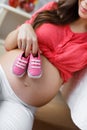 Happy future mother with pink booties in hand Royalty Free Stock Photo