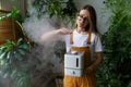 Happy gardener girl use air humidifier at home in indoor garden during heating season for plants Royalty Free Stock Photo