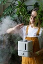 Happy gardener girl use air humidifier at home in indoor garden during heating season for plants Royalty Free Stock Photo