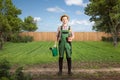 Happy gardener with a watering can and a flower pot standing in a green backyard Royalty Free Stock Photo