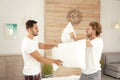 Happy gay couple having pillow fight on bed Royalty Free Stock Photo