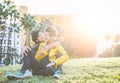 Happy gay couple hugging and laughing together sitting on grass in a park - Young women lesbians having a tender moment outdoor Royalty Free Stock Photo