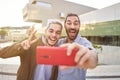 Happy gay couple taking smiling selfie with smartphone. Homosexual people having fun together.