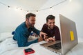 Happy gay men couple using laptop in bed Royalty Free Stock Photo