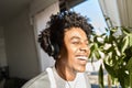 Happy gen z African American guy wearing headphones listening music at home. Royalty Free Stock Photo