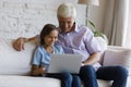 Happy grandkid boy and mature granddad watching movie on laptop