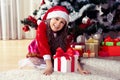 Happy gerl dressed as santa with gifts in boxes siting near a decorated Christmas tree at home closeup. Celebration of Christmas,