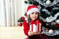 Happy gerl dressed as santa with gifts in boxes siting near a decorated Christmas tree at home closeup. Celebration of Christmas,