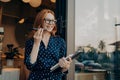 Happy ginger business woman freelancer with laptop holds mobile phone and talks on speakerphone Royalty Free Stock Photo