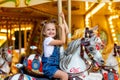 Happy girl in an amusement park rides a horse on a carousel in the summer Royalty Free Stock Photo