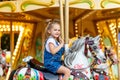 Happy girl in an amusement park rides a horse on a carousel in the summer Royalty Free Stock Photo